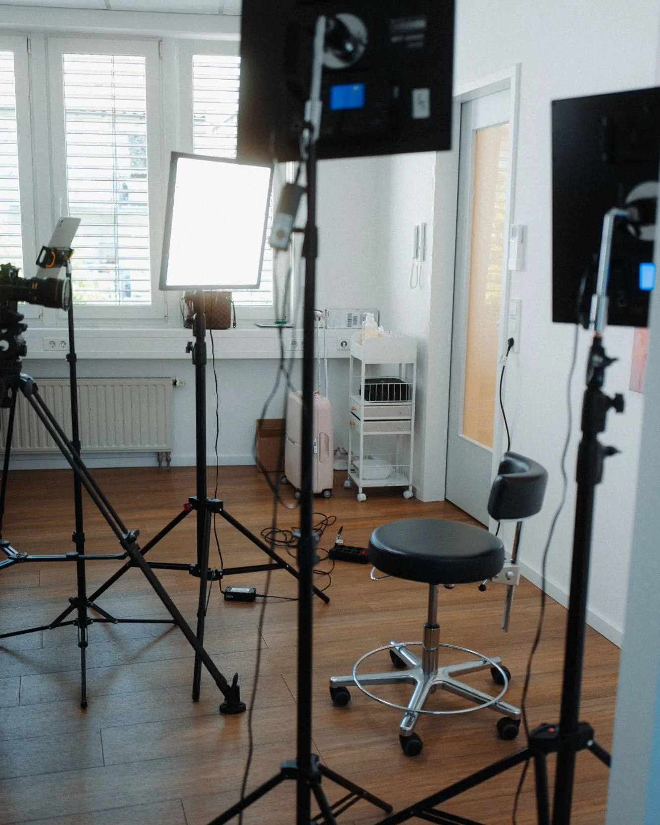 Zwei Leuchten und eine Kamera auf Stativen sind in einem Praxisraum auf einen leeren Hocker gerichtet